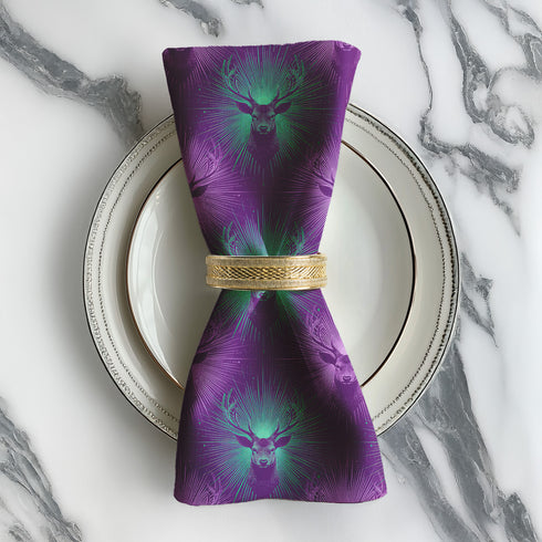 Set of four purple dining napkins featuring alternating teal and violet stag heads with radiating sunburst patterns, sized 18x18 inches.